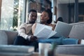 Should we reinvest this money. a young couple sitting on the sofa together and using a laptop while going through their