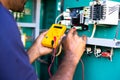 shoulder shot electrical engineer or repairman checking connection using Voltmeter on power distribution board at Royalty Free Stock Photo