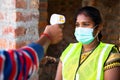 shoulder shot of man checking body tempreture of woman worker with medical face mask at workplace - concept of covid19