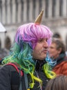Shoulder street portrait of a middle-aged man in a unicorn costume - a bright multi-colored wig resembling the mane of a unicorn