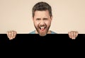 shouting bearded man behind blank black paper banner with copy space for advert, promotion