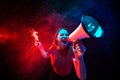 Shouting with megaphone. Young woman with smoke and neon light on black background. Highly tensioned, wide angle, fish Royalty Free Stock Photo