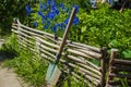 A shovel stands near a wicker rustic fence and a natural green background. Village atmosphere concept