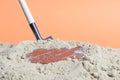 A shovel stuck in the sand there is a broken smartphone