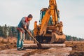 The shovel worker cleans the soil after digging the excavator, laying the road Royalty Free Stock Photo