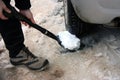 Shoveling white snow and ice with a shovel under the wheel of the car in the winter on the road to travel Royalty Free Stock Photo