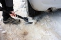 Shoveling white snow and ice with a shovel under the wheel of the car in the winter on the road to travel Royalty Free Stock Photo