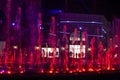 Show of multi-colored musical fountains in red tones at night Sirik against the shops, horizontal