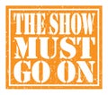 THE SHOW MUST GO ON, text written on orange stamp sign