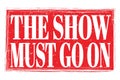 THE SHOW MUST GO ON, words on red grungy stamp sign