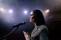 Portrait of women speaking through a microphone in dark conference hall. woman talks into microphones at press Royalty Free Stock Photo