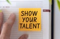 Show your talent text on light orange post-it paper pinned on notebook and hand. This message can be used in business concept Royalty Free Stock Photo