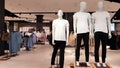 Showcase of a modern fashion store in a shopping center in the city center. Three mannequins in white t-shirts with copy space for