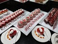 Showcase with sweets. Colored ÃÂakes on white plates on black table Royalty Free Stock Photo