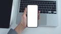Hand holds blank smartphone mockup over a laptop and tablet. Royalty Free Stock Photo