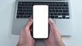 Hand holds blank smartphone mockup over a laptop and tablet. Royalty Free Stock Photo