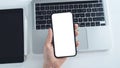 Hand holds blank smartphone mockup over a laptop and tablet. Royalty Free Stock Photo