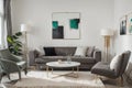 Abstract painting on grey wall o contemporary living room interior with emerald green armchair with round pillow, commode and couc Royalty Free Stock Photo