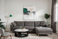 Abstract painting on grey wall o contemporary living room interior with emerald green armchair with round pillow, commode and couc Royalty Free Stock Photo