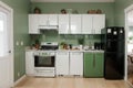 Stylish refrigerator and counters near green wall in kitchen Royalty Free Stock Photo