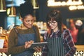 Showcasing their coffee using online tools. two young women using a digital tablet together while working at a coffee Royalty Free Stock Photo