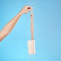 Shower, back brush and body loofah of cleaning, skincare massage or hygiene on studio blue background. Woman hands Royalty Free Stock Photo