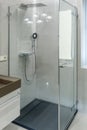 Shower cabin with transparent glass walls, rain shower and shower head. Modern bathroom design