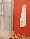 Shower cabin at wellness spa center with white bathrobe hanging on red wall