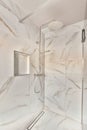 a shower with a glass door in a marble bathroom