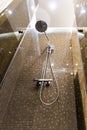 Shower head in brown shower cubicle. Bottom view, brown mosaic wall.