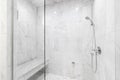A shower with marble tiles and chrome showerhead.
