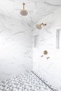 A shower with marble tiles and gold shower heads.