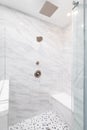 A shower with marble tiles and rock tiled floor.