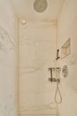 a shower with white marble walls and a shower head