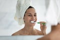 After shower woman looking in mirror and brushing her teeth