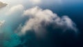 Aerial View of Deep Blue Ocean Water with a Patch of Luminous Turquoise Shallow Water and a Wispy Cloud Formation Royalty Free Stock Photo