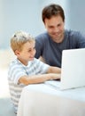 Showing dad a thing or two. Young boy on his laptop with his father next to him. Royalty Free Stock Photo