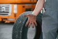 Showing dirty hands. Man in unifrom doing service for big truck vehicle