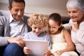 Showing granny and gramps the latest tech. A shot of two kids and their grandparents using a digital tablet while