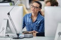 Showing her colleague how its done. Businesswoman seen between computers showing something to her colleague.