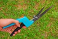 Show hand how to hold mechanical grass shears with sharp long blades & green grass in background Royalty Free Stock Photo