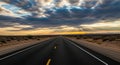 Long Desert Highway Stretching Towards a Dramatic Sunset Sky with Sun Rays Breaking Through Clouds Royalty Free Stock Photo