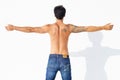 Showing off his tattoo. A handsome man with his back towards the camera and arms outstretched.