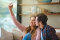 Showing their love to the world. Shot of a happy young couple taking a selfie with a smartphone while sitting on their Royalty Free Stock Photo