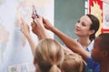 Showing them around a world map. An excited class pointing at a world map with their geography teacher. Royalty Free Stock Photo