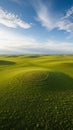 Vast Swirling Green Grass Fields Under a Bright Blue Sky with Wispy White Clouds and a Circular Pattern Royalty Free Stock Photo