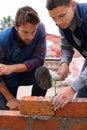 Showing the young one how its done. Shot of bricklayers at work. Royalty Free Stock Photo