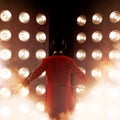 Showman Back, arms to sides. Young male entertainer, presenter or actor on stage. The guy in the red camisole Royalty Free Stock Photo