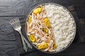 Shredded baked chicken fillet with peperoncini peppers served with rice close-up in a plate. horizontal top view
