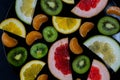 Shredded bright vivid brilliant yellow green orange red grapefruit lemon orange Mandarin kiwi sweetie in a black plate on black ba Royalty Free Stock Photo